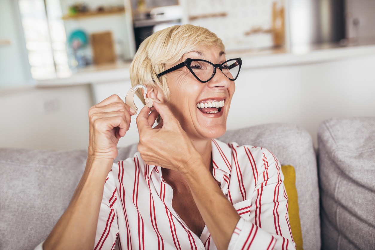 Mature woman with hearing aid indoors smiling